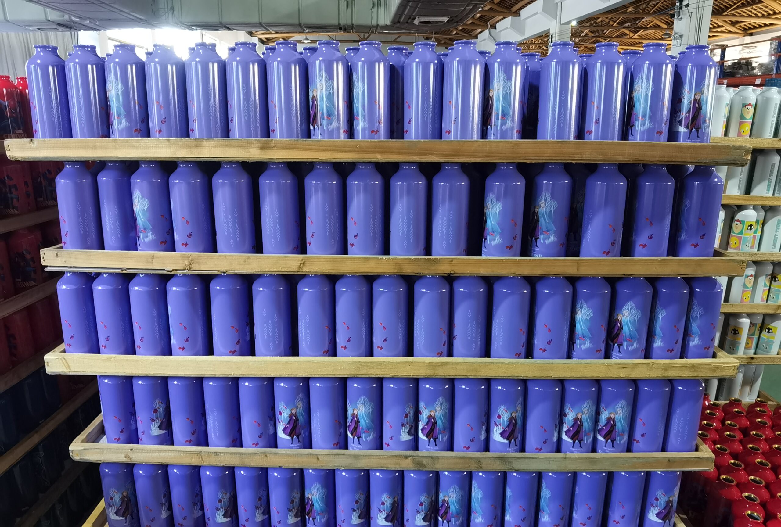 Purple bottles with printed designs on wooden shelves, factory arrangement