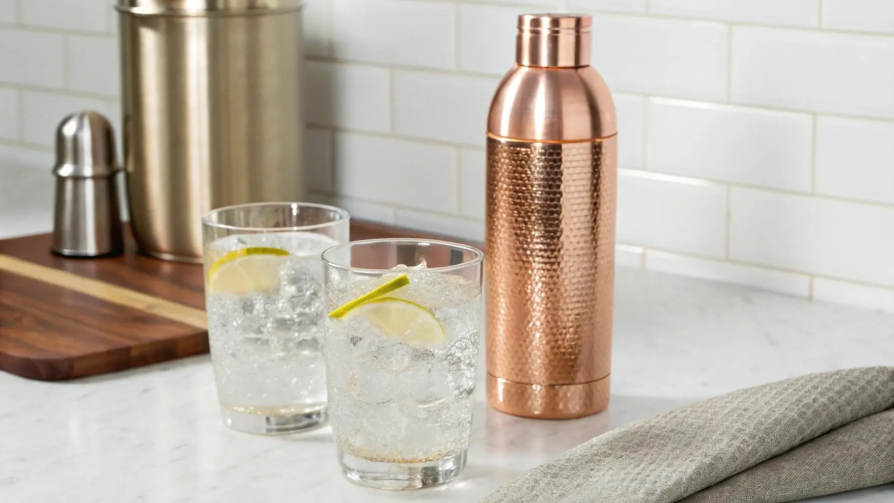Two glasses of water in front of copper and stainless steel bottles, one slightly discolored